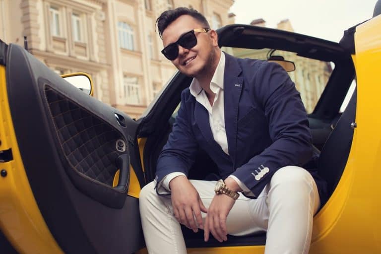 Man who is a sugar daddy in a fancy car and suit.
