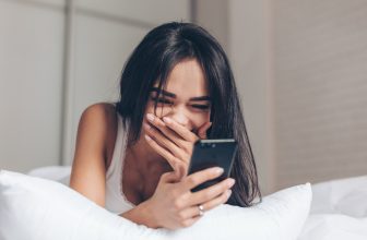 Attractive girl reading her text messages and laughing