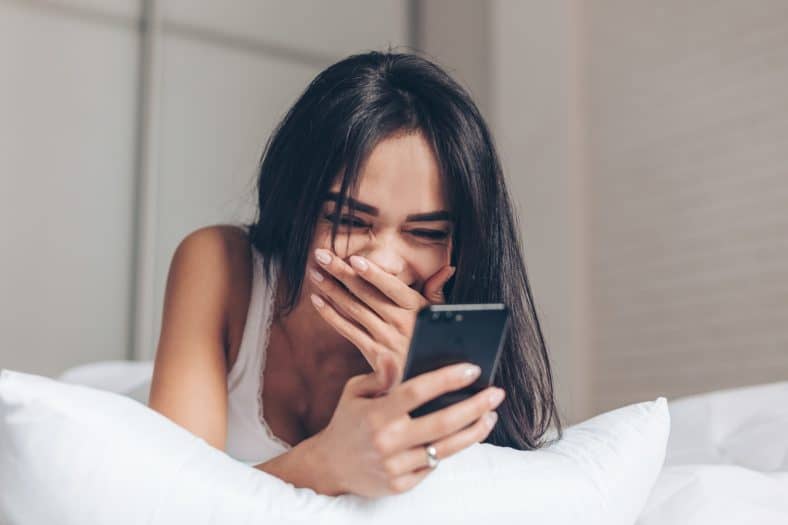 Attractive girl reading her text messages and laughing