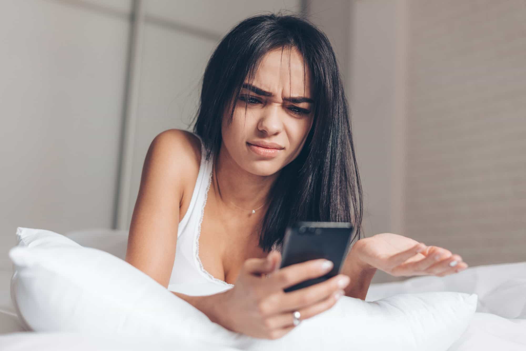 Annoyed woman using an online hookup app on her phone.