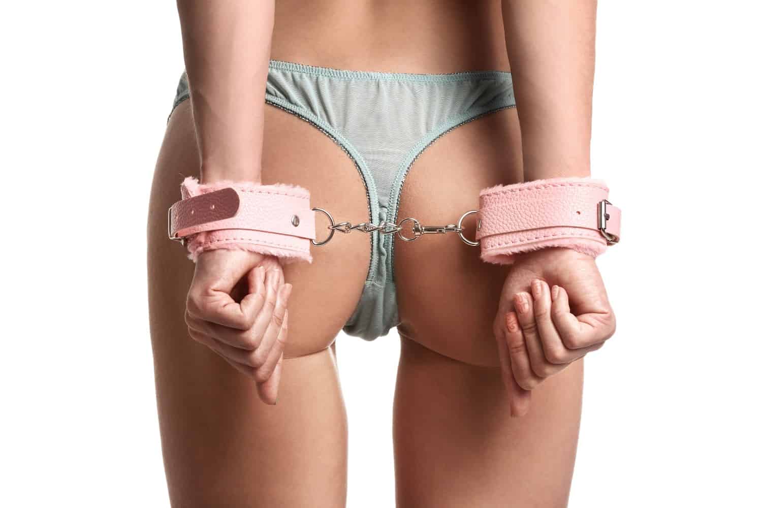 Image of a girls butt with her hand cuffed behind her back.