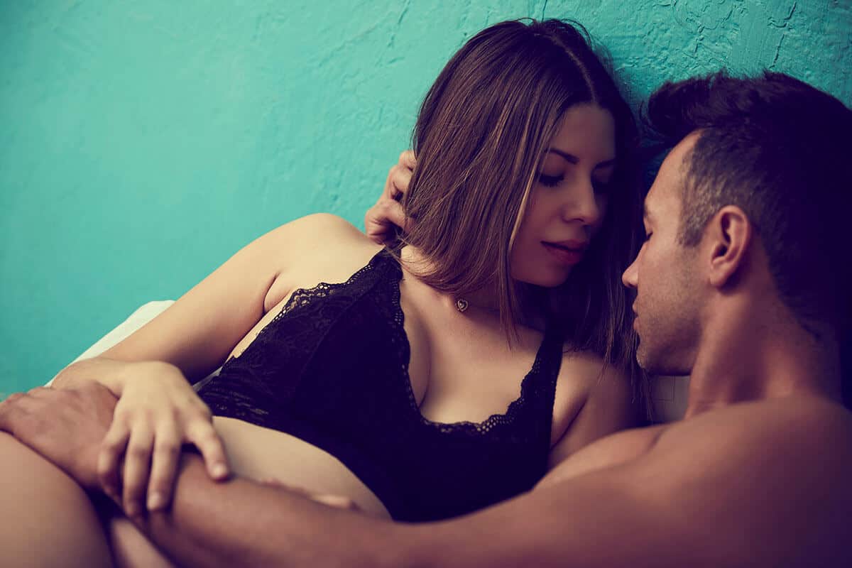 A man and woman getting ready to have sex in bed.